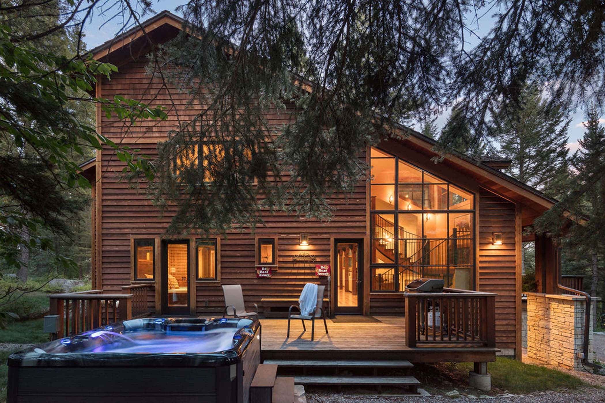 Blue Moose Lodge Exterior showcasing the back deck and hot tub in teh evening