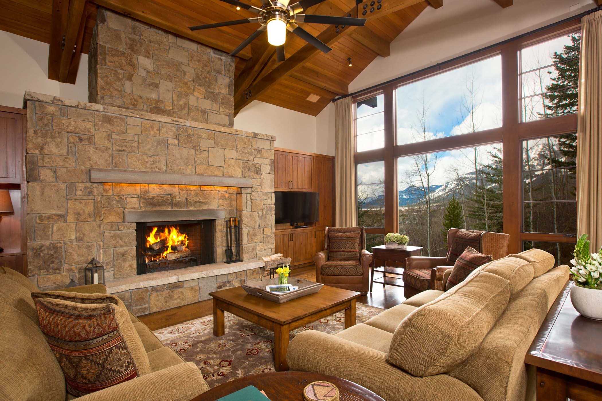 A large living space with a fireplace, lots of seating and floor to ceiling windows in a Granite Ridge Residence