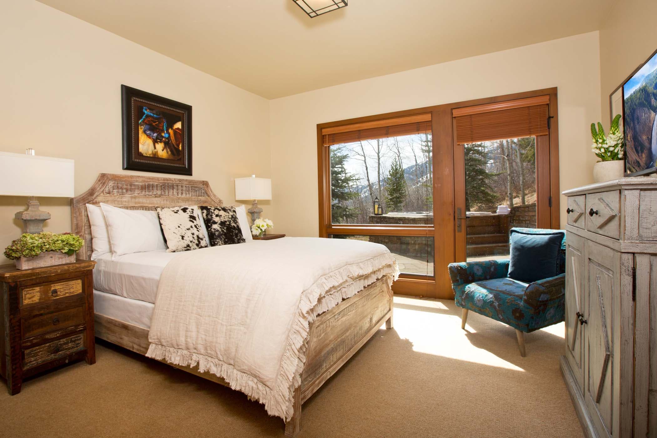 A Granite Ridge room with a queen bed, side tables, corner chair, dresser and access to outside