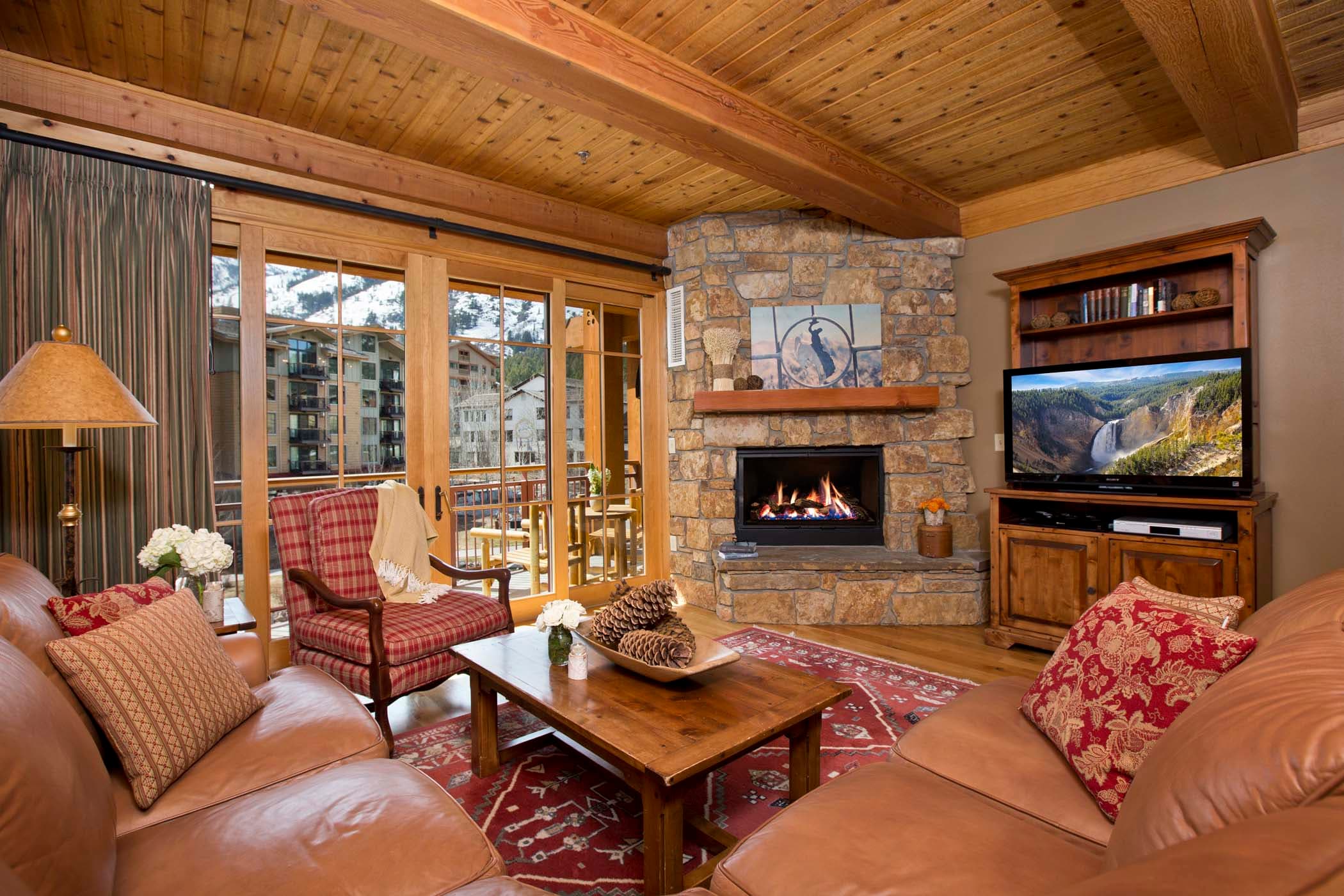 The Paintbrush living room with a TV, fireplace, love seat and couch, with access to a balcony at Teton Private Residences.
